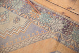 Distressed Oushak rug's faded geometric pattern, bud motifs, even wear, and intact selvage.