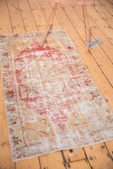 Distressed Oushak rug runner corner, showing red floral border, saffron tones, and frayed fringe.