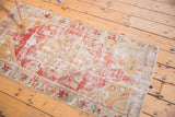 Distressed vintage Oushak rug corner, showing faded red and saffron hues with stylized border.