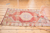 Distressed Oushak rug corner, fuchsia-red field with faint trellis and rams horn border.