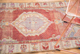 Distressed Oushak rug's red field texture, light foundation, and decorative border.