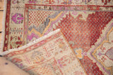 Worn cherry red pile and underlying patterned foundation of a distressed vintage Oushak rug.