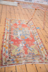 Distressed vintage Oushak rug corner, showing pale cinnabar red and dramatic leaves.