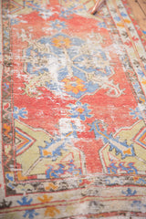 Distressed cinnabar red vintage Oushak rug, showing slate blue and tangerine leaves.