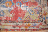 Distressed cinnabar red and slate blue Oushak rug with foundation wear and geometric border.