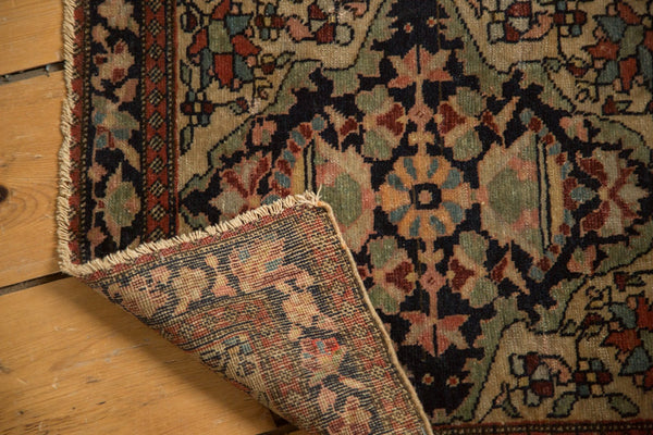 Folded corner of an antique Farahan Sarouk rug revealing its detailed hand-knotted foundation.