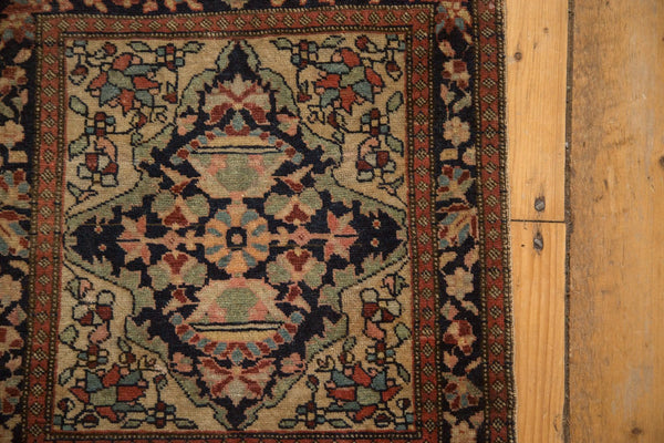 Corner view of an antique Farahan Sarouk rug with floral spandrels and a detailed border.