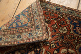 Folded vintage Farahan Sarouk rug revealing hand-knotted foundation and brick red floral pile.