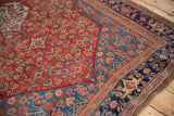 The ornate red Herati field, blue corner spandrel, and navy border of an antique Persian Bijar rug.