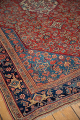 Harmonious weave of an antique Bijar rug with layered blue borders against a cherry red Herati field.