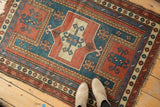 Geometric madder red and teal border on antique Farchalou Kazak rug with tattered end.