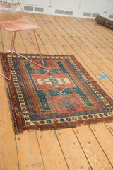 Geometric patterns and tattered edge, antique Caucasian rug in madder red, teal blue.