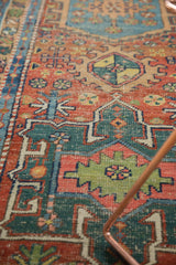 Saturated cherry red, mallard green, and sky blue geometric patterns on antique Heriz rug.