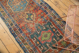 Antique Heriz runner's intricate geometric pattern in madder red, mallard green, and sky blue with low pile.