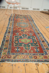 Antique Heriz runner's tattered end fringe, showing low pile and geometric design in red, green, blue.