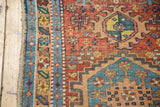 Antique Heriz rug runner's side edge, featuring geometric patterns in madder red, sky blue, and green with low pile.