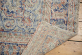 Folded vintage Distressed Oushak rug, showing mostly even wear, fringe, and woven reverse.