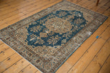 Corner view of worn Oushak rug, sky blue field, distressed beige scrolling arabesques.