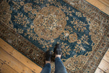 Distressed vintage Oushak rug corner with sky blue field and beige floral patterns.