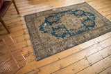 Distressed vintage Oushak rug corner with sky blue field, beige arabesques, and visible wear.