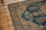 Distressed Vintage Oushak rug corner, showing sky blue and beige scrolling florals with exposed foundation.