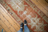 Distressed vintage Oushak runner detail: brick red field, ivory elongated leaf motifs.