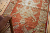 Distressed brick red field with antique ivory serrated leaf patterns, a vintage Oushak runner.