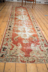 Vintage Oushak runner, showing faded cherry red and ivory distressed motifs.