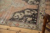 Distressed Oushak runner corner with worn pile, blush, charcoal, and ivory floral border.
