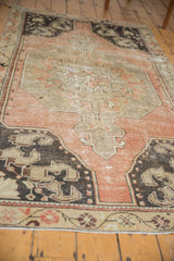 Distressed vintage Oushak rug detail with dusty rose field, charcoal spandrel, and visible knot heads.