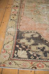 Vintage distressed Oushak runner corner, showing stylized charcoal and ivory border patterns.