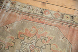 Visible wear on a distressed Oushak runner, with dusty rose, ivory, and pale yellow patterns.