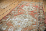 Faded brick red and beige distressed Oushak runner with noticeable foundation wear.