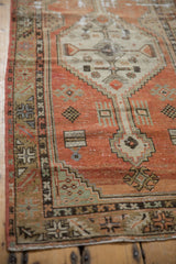 Distressed Oushak rug corner with faded brick red, seafoam green, and geometric borders.