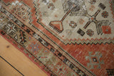 Faded brick red and ivory geometric patterns with textured wear on distressed Oushak corner.