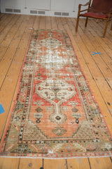 Distressed vintage Oushak runner with prominent wear, muted red tones, and visible geometric medallions.