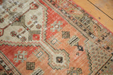 Distressed Oushak runner with faded brick red, beige, and brown geometric patterns.