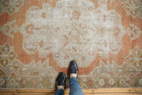 Distressed Oushak rug with serrated contours and even wear, featuring muted rust and beige.