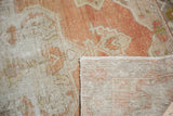 Corner of distressed Oushak rug, showing even wear on light rust pile and hand-knotted foundation.