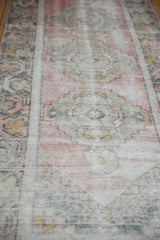 Decorative distressed vintage Oushak runner texture in soft raspberry, ivory, and dusty gold.