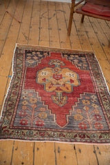 Distressed Oushak rug: lower corner spandrel with germinating plant motif, rich red and slate blue.