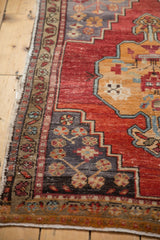 Distressed Oushak rug corner with slate blue spandrel and floral motifs, faint foundation showing.