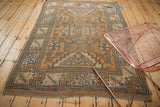 Distressed vintage Melas rug corner with bronze, ivory geometric border and secured edge.