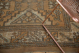 Abstract geometric border of distressed Melas rug, showing light bronze, ivory, and fringe.