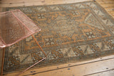 Vintage distressed Turkish Melas rug corner, with geometric patterns in bronze, ivory, and seafoam green.