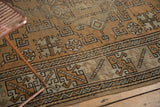 Hand-knotted vintage distressed Melas rug detail, showing geometric forms in earthy bronze and green tones.