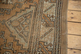Melas rug's secured side, geometric patterns, distressed pile, ivory, bronze, and stain.