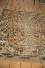 Distressed Melas rug detail showing geometric patterns, bronze hues, and a stain on the border.
