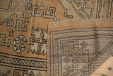 Distressed hand-knotted Melas rug with geometric bronze and ivory pattern, showing reverse.