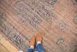 Distressed vintage Oushak carpet displaying faded apricot, royal blue, and mint curvilinear motifs.